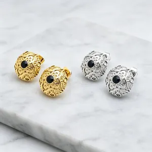 Close-up of vintage round stainless steel earrings with filigree pattern and black stone