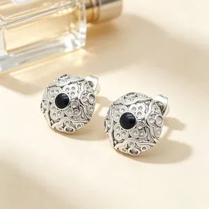 Detail view of vintage stainless steel round earrings with black stone and engraving.