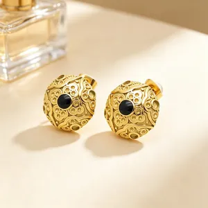 Close-up of gold vintage patterned stud earrings with black center stone