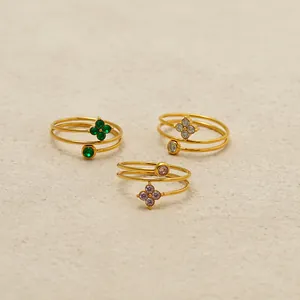 Gros plan de bagues trèfle à trois couches dorées avec zircon vert et rose