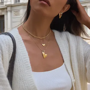 Elegantes Schmuckset mit gehämmerten Herzanhängern, 18 Karat vergoldet, an einem Model.
