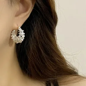 Detailed macro shot of intricate silver hollow round hoop earring on a person's ear