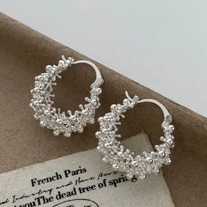 Macro view showing intricate beaded texture of silver hollow basket hoop earrings.