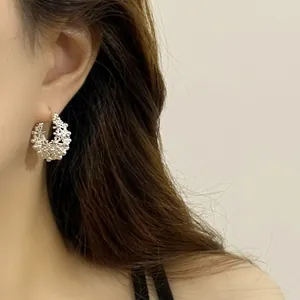 Detailed macro view showing the intricate hollow floral basket design of silver hoop earring