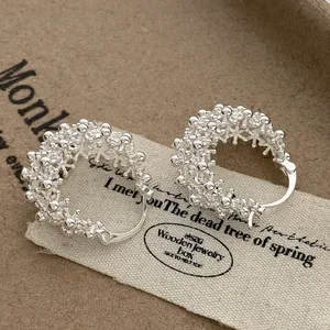 Detailed macro view of silver hollow flower basket hoop earrings with textured finish
