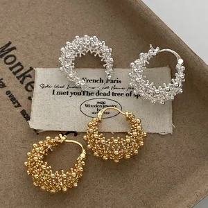 Macro view showing the intricate texture of gold and silver hollow hoop earrings.