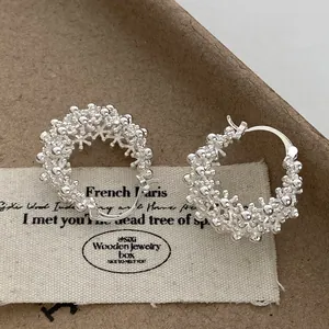 Macro view of silver-tone hollowed floral basket hoop earrings with textured beads