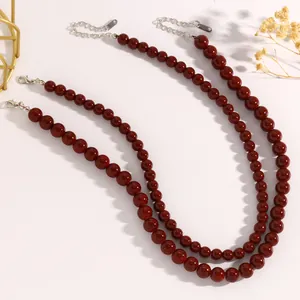 Elegante dunkelrote Perlenketten mit silbernen Karabinerverschlüssen im Detail.