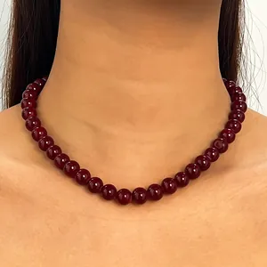 Elegante Halskette mit dunkelroten runden Perlen am Hals getragen Nahaufnahme Detail