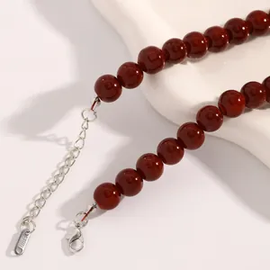 Detailansicht einer dunkelroten Perlenkette mit Edelstahl-Karabinerverschluss und Kette.