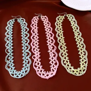 Vue détaillée de trois colliers en perles d'œil de chat pastel sur tissu marron.