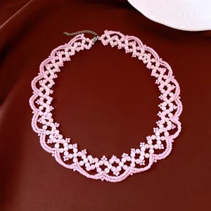 Détail du collier ras de cou en dentelle perlée rose œil de chat sur satin marron.