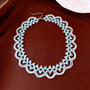 Détail complexe d'un collier ras du cou en dentelle florale perlé œil-de-chat bleu clair