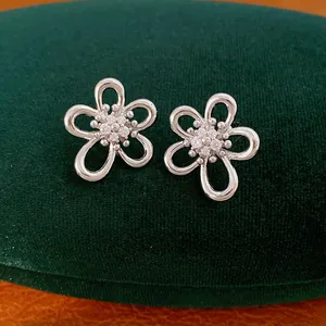 Primo piano di orecchini a lobo a forma di fiore cavo in argento con zirconi