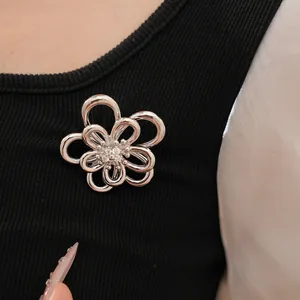 Elegante spilla a fiore cavo in argento con centro in CZ appuntata su un top nero