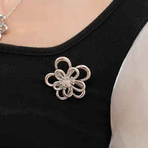 Dettaglio di ciondolo a fiore traforato in argento con zirconi su tessuto nero