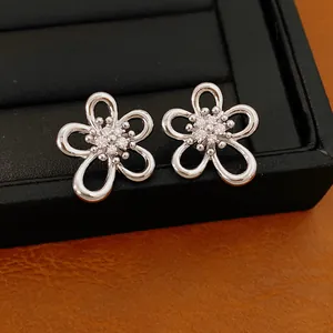 Dettaglio di orecchini a fiore traforato argentati con intarsi in zirconia scintillante