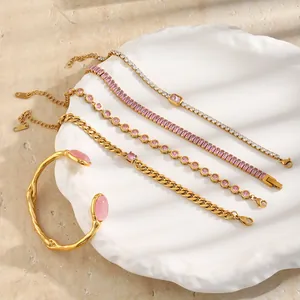 Vista dettagliata di bracciali e polsini in acciaio inossidabile dorato con pietre rosa su vassoio