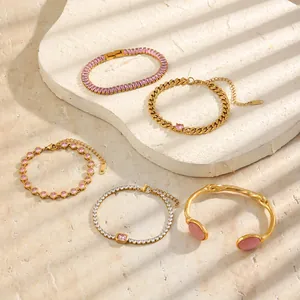 Dettaglio di eleganti bracciali in acciaio inossidabile dorato con pietre di zircone rosa.