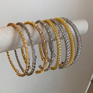Elegante goldene und silberne gedrehte Metallarmreifen auf einem weißen Displayständer