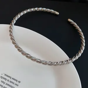 Minimalistischer, gedrehter silberner Metall-Choker auf einem weißen Keramikteller