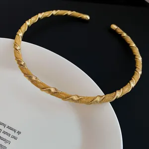 Detailansicht eines eleganten goldfarbenen Chokers mit gedrehter Textur auf einem Teller