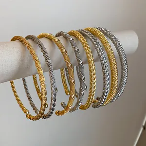 Detailansicht von eleganten gedrehten und geflochtenen Metallarmreifen in Gold und Silber