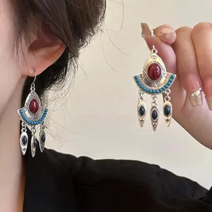 Detailopname van etnische kwastoorbellen met turquoise en rode stenen in vintage stijl