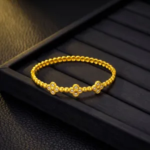 Vista dettagliata del bracciale con motivo a quadrifoglio dorato e cristalli su base nera.