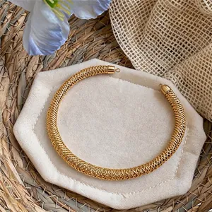 Dettaglio di un girocollo in maglia dorata con una trama intrecciata complessa