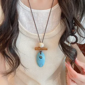 Close-up of retro blue resin geometric pendant necklace styled on a white knit top.