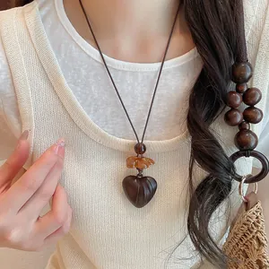Detail view of a vintage brown resin heart pendant necklace worn on a cream knit top