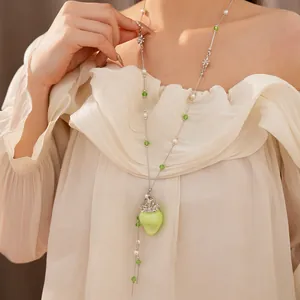 Exquisites Detail einer süßen grünen Erdbeer- und Perlenkette an einem Model im Freien
