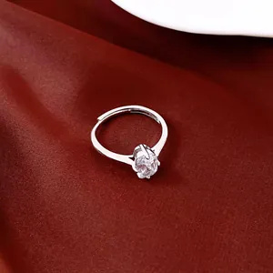 Nahaufnahme eines silbernen Rings mit funkelndem ovalem Zirkonia auf roter Seide.