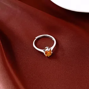 Detailansicht eines silbernen Rings mit einem orangefarbenen Zirkon auf rotem Satin