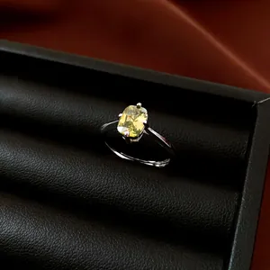 Nahaufnahme eines silbernen Rings mit ovalem grünem Zirkon auf schwarzem Leder.