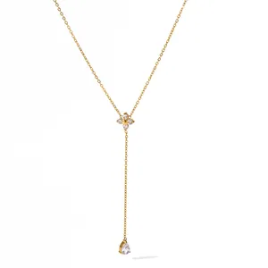 Detailed macro view of gold stainless steel necklace with clover and pear-shaped pendant