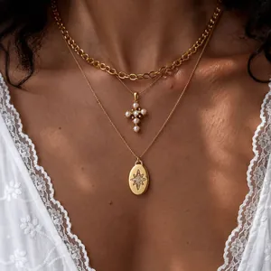 Close-up of layered gold necklaces with pearl cross and rhinestone starburst pendant