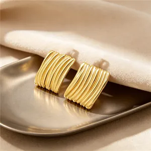 Gros plan de boucles d'oreilles en acier doré avec texture de relief rayée chic