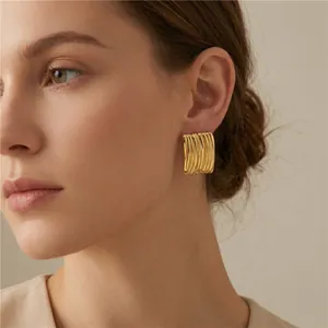 Gros plan de boucles d'oreilles rayées en acier inoxydable doré avec texture en relief