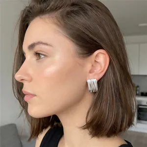 Gros plan de boucles d'oreilles argentées à rayures portées par un mannequin de mode