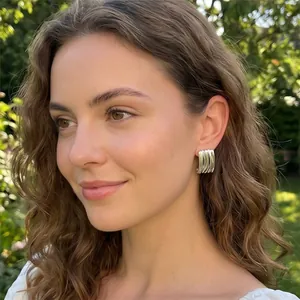 Gros plan d'un mannequin portant des boucles d'oreilles rayées argentées en plein air.
