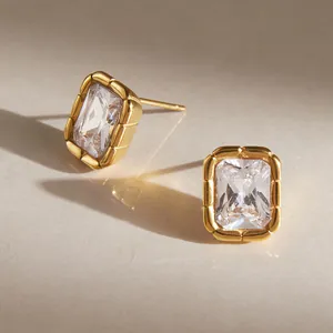 Macro view of gold-plated ribbed bezel stud earrings with rectangular clear zircon
