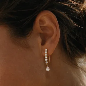 Macro view of elegant gold stainless steel earrings featuring sparkling teardrop zircons.