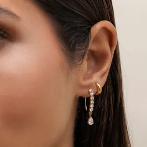 Detail of gold stainless steel dangling earrings with shimmering cubic zirconia drops.