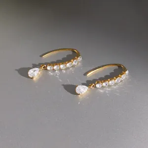 Detail shot of gold-plated titanium steel earrings with sparkling teardrop zirconia.