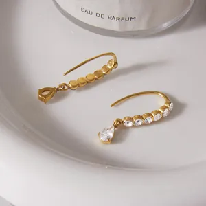 Detailed view of gold stainless steel earrings with sparkling teardrop zirconia stones