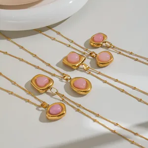Close-up detail of golden stainless steel necklaces with various pink crystal stone pendants