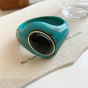 Detailed macro view of chunky marbled turquoise acrylic bangle with black oval stone.