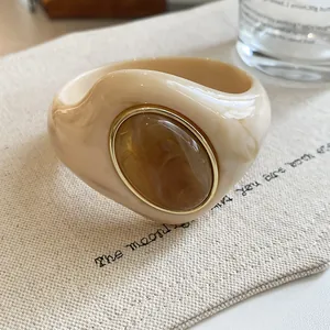 Detailed macro view of a chunky marbled acrylic bracelet with a gold-rimmed resin inlay.